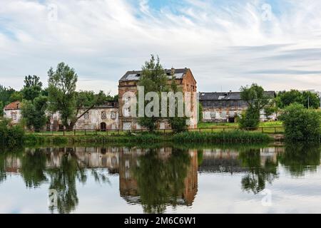 L'ancien bâtiment abandonné en briques se reflète dans l'eau Banque D'Images