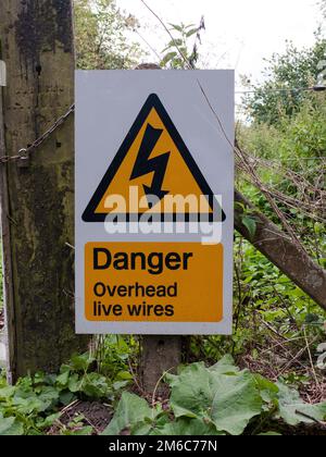 Avertissement triangle jaune danger câbles sous tension aériens Banque D'Images