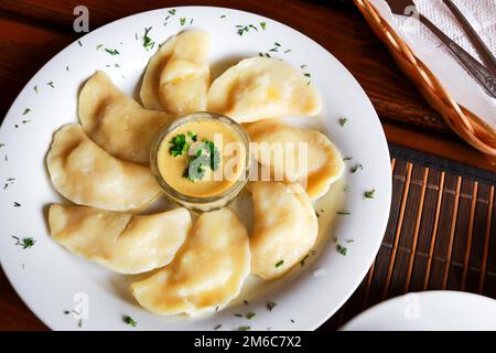 Plat vareniki russes et ukrainiennes avec une purée de pommes de terre et la crème fraîche et champignons sur plaque blanche. Close up. Banque D'Images