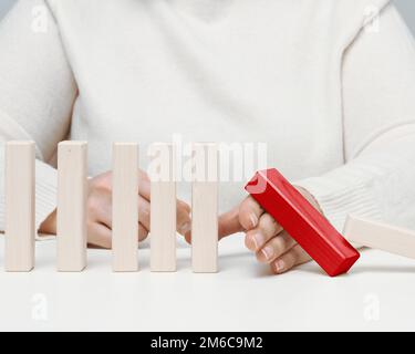 La main arrête la chute de blocs de bois sur un fond blanc. Concept d'une personnalité forte et courageuse capable de résister à des difficultés inégales Banque D'Images