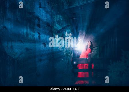 Femme avec lumière magique dans une forêt sombre Banque D'Images