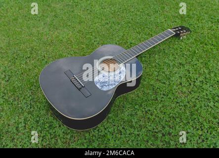 Guitare acoustique noire. Repose sur l'herbe Banque D'Images