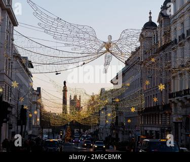 Spiritueux de Noël suspendus au-dessus de Regent Street St James. Waterloo place et chambres du Parlement derrière Londres, Angleterre. Banque D'Images