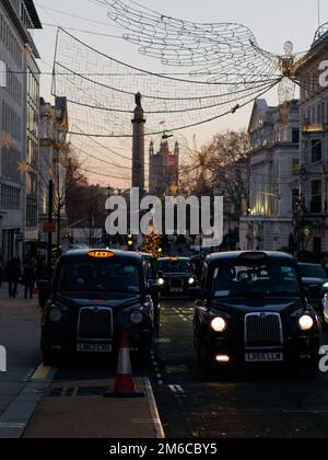 Spiritueux de Noël suspendus au-dessus de Regent Street St James. Waterloo place et chambres du Parlement derrière Londres, Angleterre. Banque D'Images