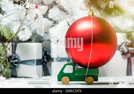 Voiture en bois avec boule de noël décoration rouge sur un fond de lumières brillantes Banque D'Images