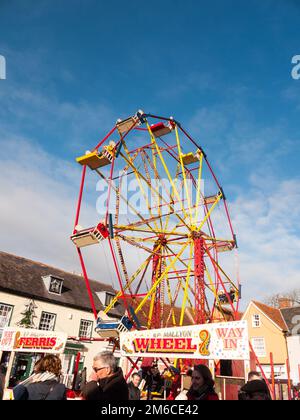 Roue de carrousel rouge et jaune à l'extérieur avec des personnes au-dessous du ciel bleu salon de noël Banque D'Images