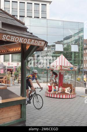 Aachen. Cologne - Allemagne 24-08-2021. Paysage urbain en août du centre d'Aix-la-Chapelle. Cycliste de ville, garçon sur le carrousel, comptoir de chocolat Banque D'Images