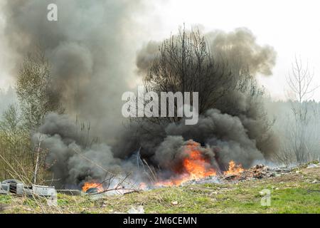 Feu dans la nature. Une décharge illégale est en feu. Fumée noire et feu. Banque D'Images