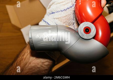 Paris, France - 4 juillet 2022 : gros plan de la main lors du déballage du nouvel adaptateur haut-de-gamme pour aspirateur Dyson V12 Detect Slim Absolute sans fil puissant aspirateur cyclonique coloré sans fil Banque D'Images