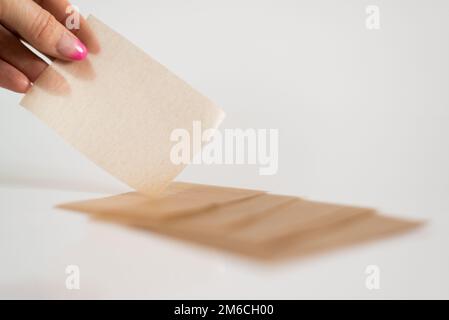 Serviettes cosmétiques de tapis pour enlever le brillant gras du visage dans la main de la femme. Banque D'Images