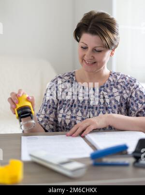 Une femme comptable met le sceau sur les documents Banque D'Images