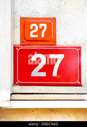 Numéro 27. Plaque rouge avec un numéro vingt-sept sur un mur. Banque D'Images
