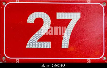 Numéro 27. Plaque rouge avec un numéro vingt-sept sur un mur. Banque D'Images