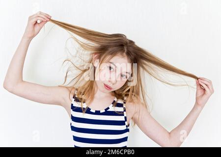 Jolie fille jouant avec des cheveux longs blonds sur blanc Banque D'Images