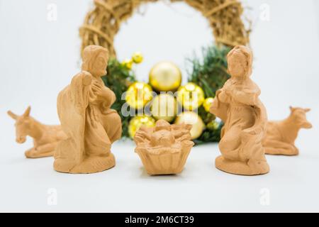 Lit bébé de Noël. Figurines en terre cuite de bébé Jésus, Vierge Marie, Saint Joseph et couronne sur blanc. Banque D'Images