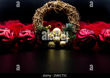 Couronne de Noël et décorations avec boules rouges et tissu sur noir. Banque D'Images