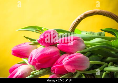 Beau bouquet de tulipes roses dans un panier en osier Banque D'Images