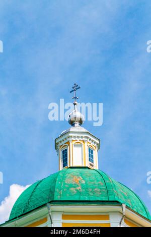 Église chrétienne orthodoxe jaune avec un dôme vert en été contre un ciel bleu avec des nuages blancs. Banque D'Images