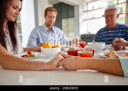 Manger, prier, aimer. une famille disant une prière avant de manger leur nourriture. Banque D'Images