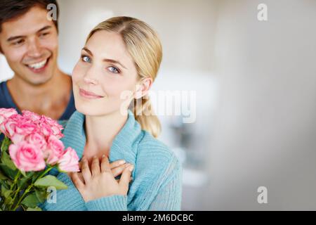 Amour fleuri. un jeune homme affectueux donnant à sa belle jeune femme un bouquet de roses roses. Banque D'Images