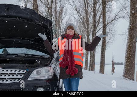 Une jeune femme sans défense a une panne de voiture en hiver Banque D'Images