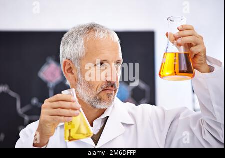 Observation des réactions chimiques en laboratoire. un scientifique mâle mature examinant les résultats d'une expérience dans son laboratoire. Banque D'Images