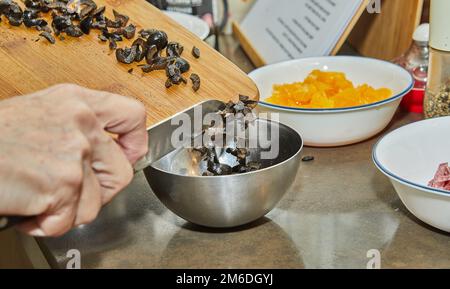 Le chef déporte les olives en salade avec des courgettes, des oranges et du salami. Cuisine gastronomique française, sur fond de bois. Banque D'Images