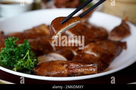 Hambourg, Allemagne. 02nd janvier 2023. Un homme saisit un morceau de canard croustillant avec des baguettes à une table dans le restaurant chinois 'Dim Sum Haus'. Le restaurant chinois traditionnel 'Dim Sum Haus' est le plus ancien restaurant chinois de la ville et est exploité par la troisième génération depuis 1964. (À dpa 'Sweet and Sour anniversaire: 100 ans of Chinese restaurants') Credit: Marcus Brandt/dpa/Alamy Live News Banque D'Images