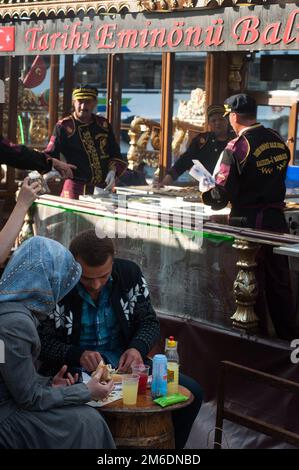 Un couple turc mangeant un sandwich au poisson la célèbre nourriture de rue Balik Ekmek à côté de la Corne d'Or, I Banque D'Images