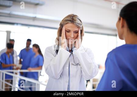 C'était une longue journée à l'hôpital. un médecin surtravaillé parlant à une infirmière dans un couloir d'hôpital. Banque D'Images