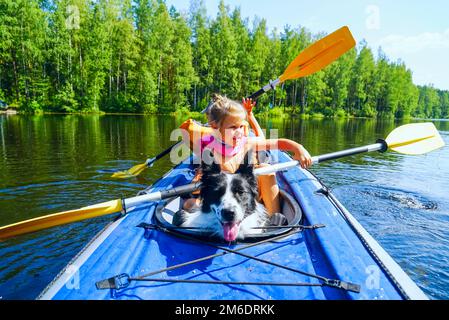 Une fille avec un chien assis dans un kayak sur le lac . Banque D'Images