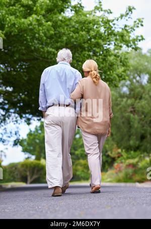 Je me rendaient à la maison. Vue arrière d'un couple senior en train de faire une promenade. Banque D'Images