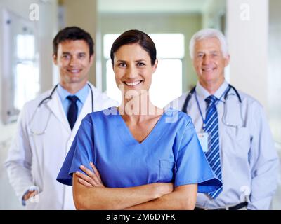 Votre équipe médicale amicale. Portrait de trois médecins souriants debout dans un couloir. Banque D'Images