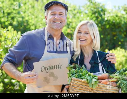 Frais de la ferme. Un couple fermier mature tenant un panier de légumes fraîchement cueillis. Banque D'Images