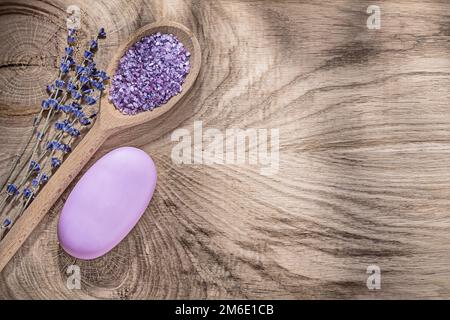 Composition d'une cuillère en bois sel de mer parfum lavande morceau de savon sur bois planche de papier espace copie concept de santé. Banque D'Images