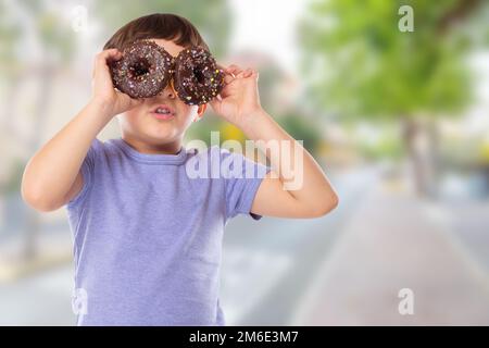 Petit garçon enfant avec beignes beignes ayant plaisir bonheur heureux ville malsain manger Banque D'Images