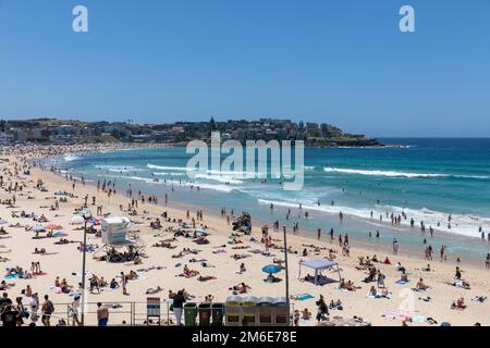 Été 2023, Bondi Beach Sydney sur un ciel bleu clair jour d'été, plage pleine et bondée avec les gens de bains de soleil et de natation, Sydney, NSW, Australie Banque D'Images