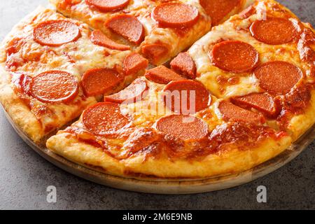 Pizza au pepperoni chaud fraîchement cuite avec saucisses, mozzarella et sauce tomate sur une planche de bois sur la table. horizontale Banque D'Images