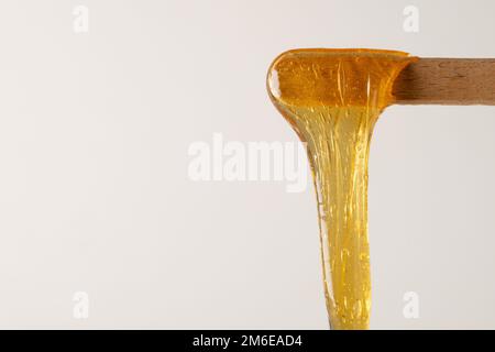 Pâte de sucre jaune liquide ou cire pour l'épilation sur bois colle ou spatule Banque D'Images
