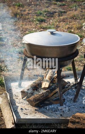 Cuisine à l'extérieur, cuisine au pieu, chaudron métallique sur le feu. Préparation d'un aliment en choux-fleurs noirs utilisés au feu ouvert, repas de camping. Sélectif f Banque D'Images