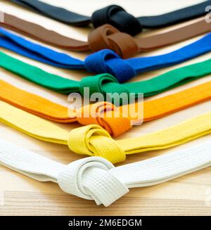Ceintures colorées pour les arts martiaux sur fond de bois. Banque D'Images
