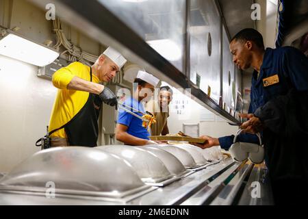 LE chef de commandement DE LA MER DES PHILIPPINES (26 avril 2022), Joel Rodriguez, de Woodland, en Californie, sert de la nourriture dans la cuisine à bord du porte-avions de la classe Nimitz USS Abraham Lincoln (CVN 72). Abraham Lincoln Strike Group est en cours de déploiement prévu dans la zone d'exploitation de la flotte américaine 7th afin d'améliorer l'interopérabilité par le biais d'alliances et de partenariats tout en servant de force de réaction prête à l'emploi pour soutenir une région libre et ouverte d'Indo-Pacifique. Banque D'Images