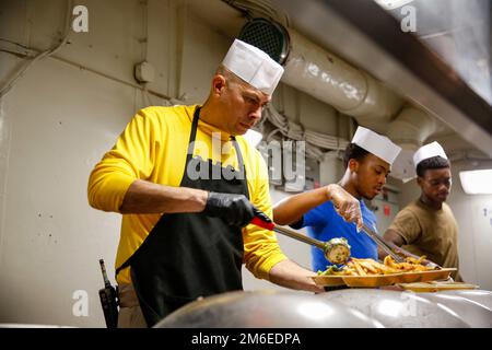 LE chef de commandement DE LA MER DES PHILIPPINES (26 avril 2022), Joel Rodriguez, de Woodland, en Californie, sert de la nourriture dans la cuisine à bord du porte-avions de la classe Nimitz USS Abraham Lincoln (CVN 72). Abraham Lincoln Strike Group est en cours de déploiement prévu dans la zone d'exploitation de la flotte américaine 7th afin d'améliorer l'interopérabilité par le biais d'alliances et de partenariats tout en servant de force de réaction prête à l'emploi pour soutenir une région libre et ouverte d'Indo-Pacifique. Banque D'Images