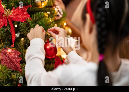 Petite fille décorer arbre de noël avec ornement. Banque D'Images