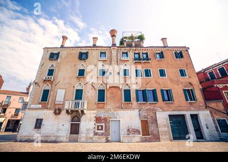 Ancien bâtiment avec fenêtres et cheminées et une façade abîmée Banque D'Images