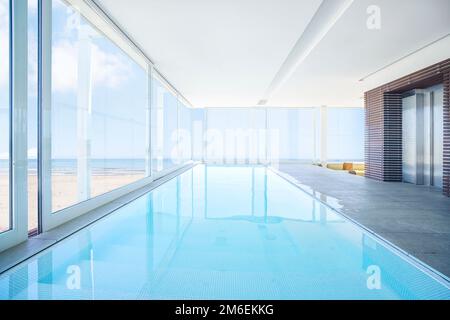 Piscine intérieure de luxe au bord de la plage en été avec eau turquoise et océan en arrière-plan Banque D'Images