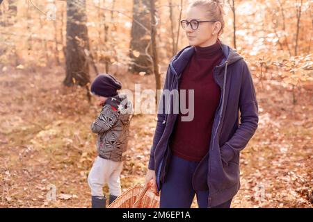 Femme avec son fils dans la forêt d'automne sur une promenade. Fille dans les bois. Banque D'Images