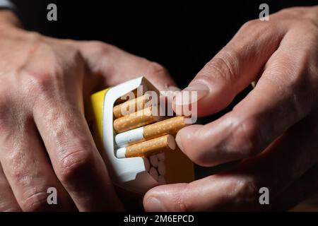 gros plan homme main tenant peler le paquet de cigarettes préparer fumer une cigarette. Ligne d'emballage Banque D'Images