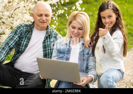 Trois générations de famille assis à l'extérieur dans la nature de printemps Banque D'Images