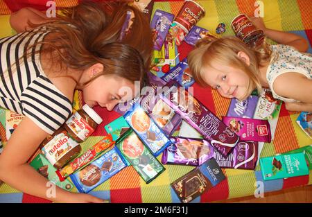 Les enfants heureux se trouvent dans un tas de bonbons et de chocolats. Les enfants s'amusent Banque D'Images